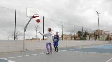 Sokakta basketbol oynayan genç bir kadın.