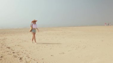 Güzel kız kumsalda yürüyor.