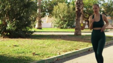 Spor yapan genç bir kadın şehir parkında esneme hareketleri giyer. Spor giyim sektöründe bayan sporcu.