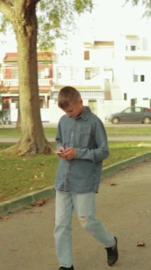 Genç bir adam parkta cep telefonu kullanıyor..