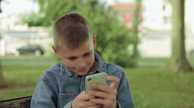 Parkta akıllı telefonu olan genç bir adam.