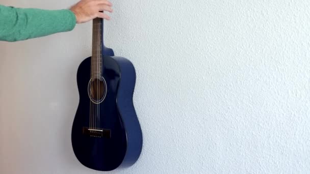 Una Mano Hombre Quita Una Guitarra Una Pared Blanca Primer — Vídeos de Stock