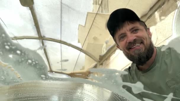 Glücklicher Mann Wäscht Autoscheibe Mit Einem Druckstrahl Verschwommenes Glas Durch — Stockvideo