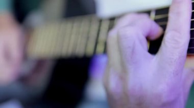 Gitar çalmak için. Bir müzisyen müzik çalar. Erkek parmakları. Bir adamın eli karanlık bir odada gitar çalar. Tanınmayan bir adam akbabaya yakın çekim provası yapıyor. Yüksek kalite 4k görüntü