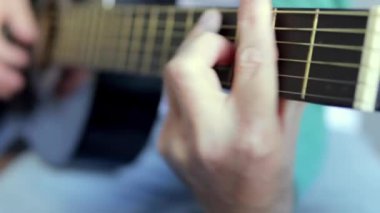 Gitar çalmak için. Akustik gitar çalıyor. Bir müzisyen müzik çalar. Bir adamın eli odada gitar çalar. Tanımlanamayan bir adam prova yapıyor, yakın çekim yapıyor. Yüksek kalite 4k görüntü