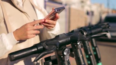 Turist kız motosikletini park yeri ve turist telefonu paylaşımında kullanıyor. Çevre taşımacılığı. Dostça ulaşım yöntemleri. Yüksek kaliteli FullHD görüntüler