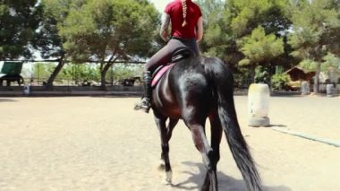 Siyah beyaz elbiseli genç kız otlakta ata biniyor..