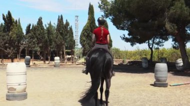 Genç bir kadın çiftlikte ata biniyor.