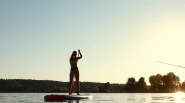 Genç bir kadın gölde kürek çekiyor.