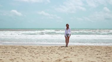 Genç bir kadın sahilde koşuyor.