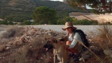 Genç bayan yürüyüşçü yazın dağlarda bir köpekle yürüyor..