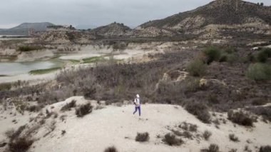 Beyaz gömlekli bir adam ve kumsalda bir sırt çantası.