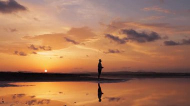 Sahilde gün batımında bir kızın silueti..