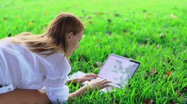 Çimlerin üstünde a laptop ile genç kadın