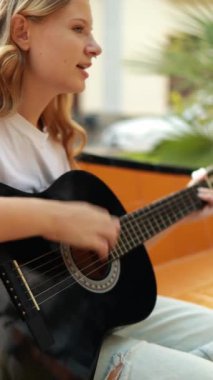 Gitar çalan genç, güzel sarışın kadın.