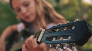 Parkta gitar çalan kadın, yakın plan. Yaz, eğlence ve hobi konsepti.