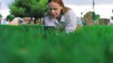 Parkta dizüstü bilgisayarı olan genç bir kadın.