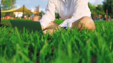 Beyaz gömlekli kadın yeşil çimlerde çalışıyor..
