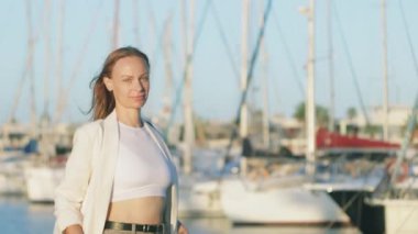 Beyaz ceketli ve beyaz gömlekli genç bir kadın iskelede yürüyor.