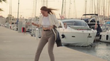 Marinada bir iskelede yürüyen genç bir kadın.