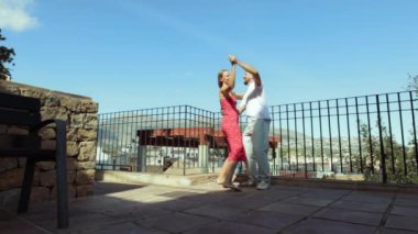 Mutlu genç çift bir yaz günü balkonda zıplarken eğleniyor ve dans ediyor..