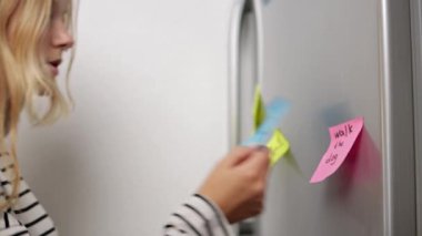 Kalemle yapışkan bir not tutan kadın