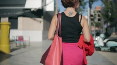 Pembe etekli kadın bacakları ve sokakta siyah deri çanta..