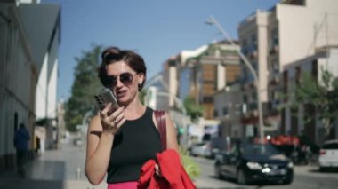 Şehirde cep telefonu kullanan genç bir kadın.