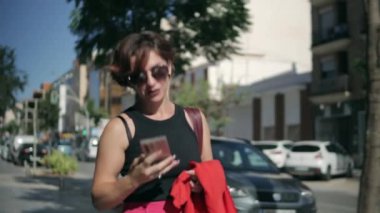 Şehir sokağında cep telefonu olan genç bir kadın.
