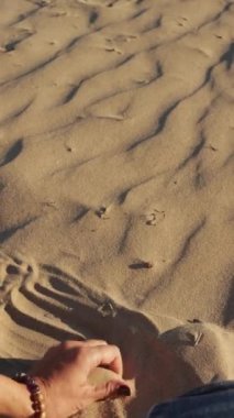 Adamın eli çölde bir kumu tutuyor.