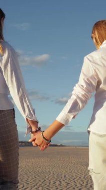 Çift el ele tutuşarak ve sahilde yürüyüş.
