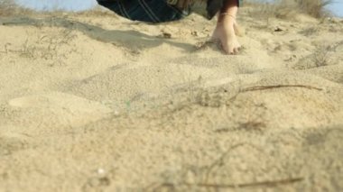 Çölde kumların üzerinde uzun saçlı, beyaz elbiseli güzel bir kız.