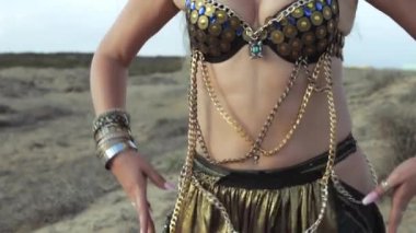 Sıcak ve güneşli bir günde çölde altın bir kolye takan seksi bir kadın.