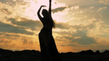 Gün batımında dans eden kadın silueti..