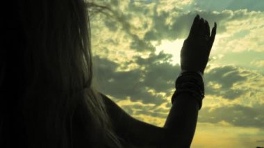 Kumsalda sırt çantalı bir kadının silueti.