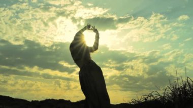 Gün batımında bir buğday tarlasında ellerini kaldırmış siluet genç kız. Özgürlük kavramı