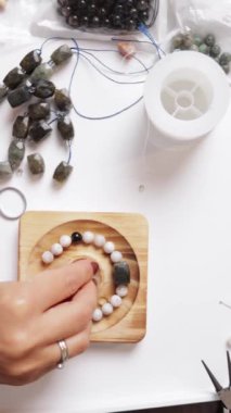 Tahta masadaki beyaz kolyeli bir kadının yakın plan fotoğrafı.