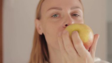 Kadın elinde elmayla elma yiyor.