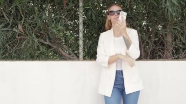 Güneş gözlüklü genç kız telefonda konuşuyor.