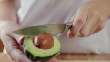 Adam tahtadan bir parça avokado kesiyor.