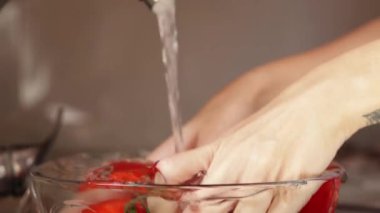 Mutfak lavabosunda domates yıkayan kadın.