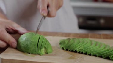 Mutfakta yeşil avokado kesiyor.