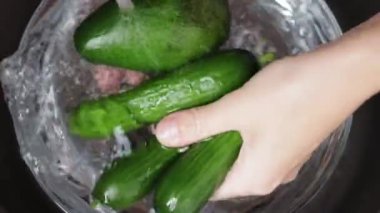 Yeşil bir salatalık tutan bir kadının ellerini yakın çekim.