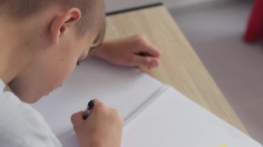 Delikanlı odada ödev yapıyor.