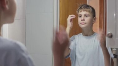Genç adam banyoda aynaya bakıyor.
