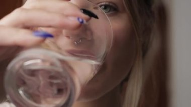 Kadın mutfaktaki şişeden su içiyor.