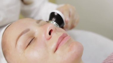 Genç bir kadın güzellik salonunda yüz bakımı görüyor.