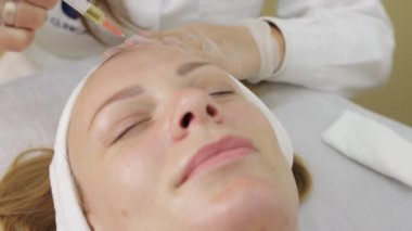 Bir kadın genç ve güzel bir kızın yüzüne yüz maskesi yapar.