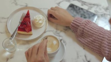 Kafede elinde bir bardak sıcak içecek tutan bir kadın.