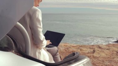 Elinde dizüstü bilgisayar olan beyaz ceketli bir kadın.